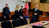 Der Angeklagte Torben S. (mit Ordner vor Gesicht) wird in den Gerichtssaal geführt