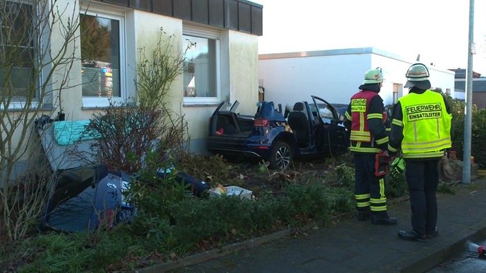 Das beschädigte Unfallauto ohne Dach vor der Hauswand