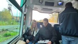 Eine Frau und ein Mann sitzen in einem autonom fahrenden Bus
