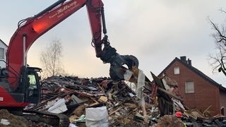 Ein Bagger trägt die Trümmer des eingestürzten Hauses ab