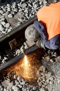 Ein Bauarbeiter schweißt ein Stück Schiene auf einer Bahn-Baustelle