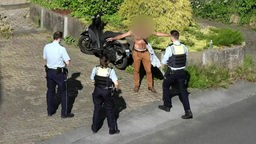 Polizisten umzingeln einen Mann mit nacktem Oberkörper