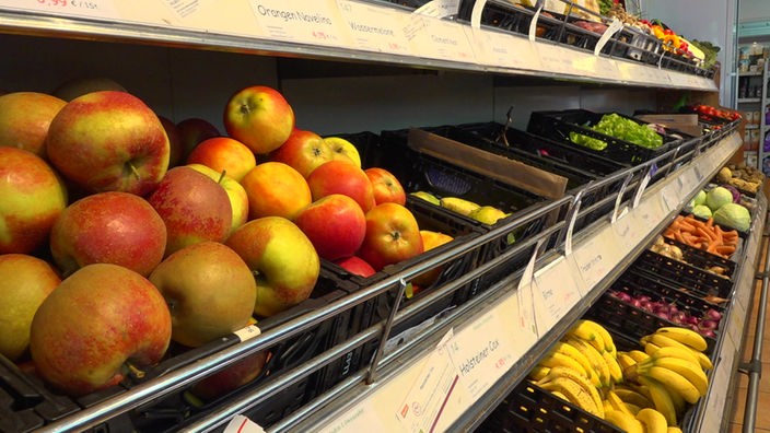 Die Obst- und Gemüse-Abteilung eines Bio-Supermarkts. Im Vordergrund sind mehrere Kisten mit Äpfeln zu sehen.