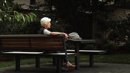 Eine Seniorin sitzt an einem Tisch im Pocket-Park.