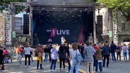 Viele Menschen stehen vor einer Bühne mit Musikern