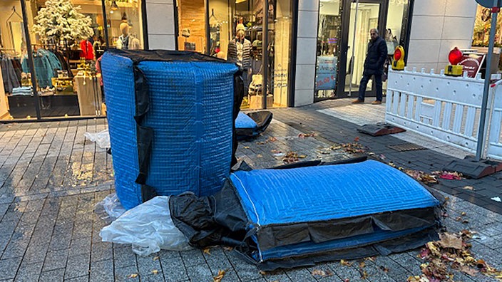 Das Bild zeigt drei Wassercontainer, zwei zerstörte und einen intakten