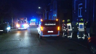 Feuerwehrautos, Krankenwagen und Rettungskräfte stehen bei Dunkelheit mit Blaulicht vor einem Zechenhaus in Bottrop, in dem Kohlenmonoxid ausgetreten ist