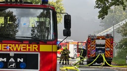 Drei Feuerwehrmänner arbeiten zwischen den drei stehenden Feuerwehrautos.