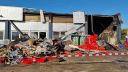 Vor einer abgebrannten Halle liegt verbrannter Schutt