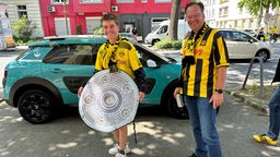 Zwe Dortmund-Fans aus Frankfurt haben eine Papp-Meisterschale in der Hand