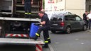 Ein Polizist hebt ein blaues Chemikalienfass auf einen LKW