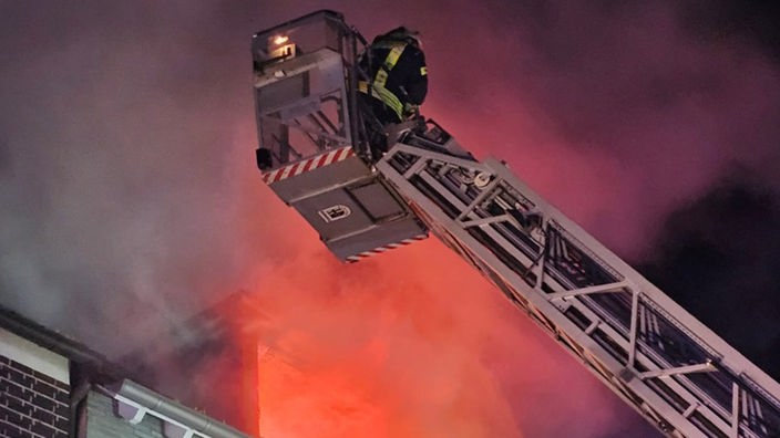 Ein Feuerwehrmann löscht ein Feuer im Dachgeschoss.