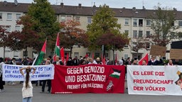 Demonstranten stehen mit Plakaten und Bannern auf einem Platz