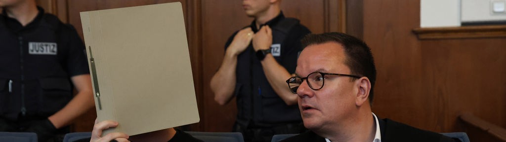 Im Gerichtssaal verbirgt der angeklagte Schütze sein Gesicht hinter einer Mappe, neben ihm sitzt sein Verteidiger Christoph Krekeler