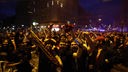 Auf dem Foto ist eine große Menschenmasse im Dunkeln. Ein Fan hält strahlend einen Galatasaray-Schal in die Kamera.