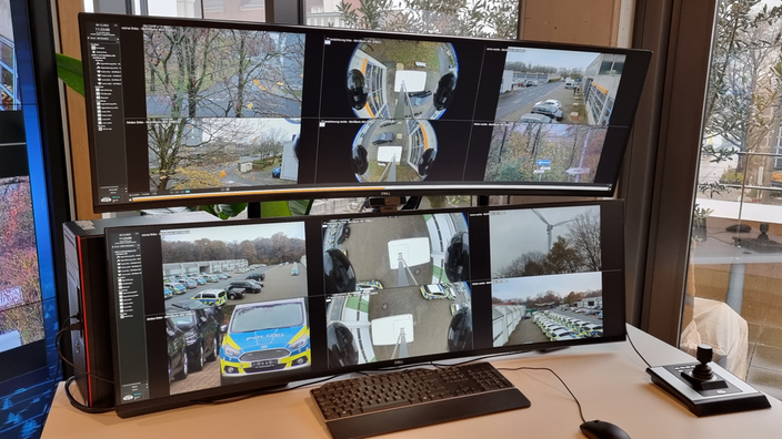 Auf einem Schreibtisch stehen sechs Bildschirme, die zur Videoüberwachung genutzt werden