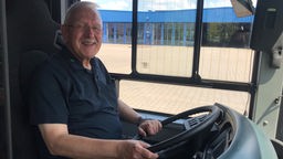 Busfahrer Jürgen Klein sitzt in der Fahrerkabine eines neuen E-Busses.