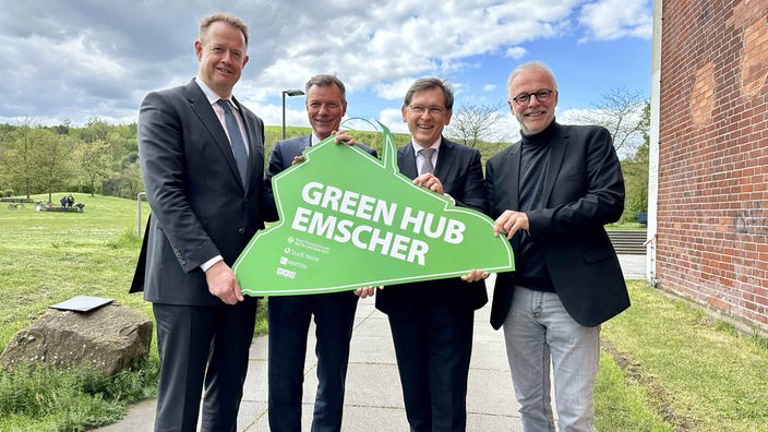 Die Bürgermeister von Recklinghausen, Herten und Herne und der Geschäftsführer der RAG Montan-Immobilien halten ein grünes Schild, auf dem "Green Hub Emscher" steht