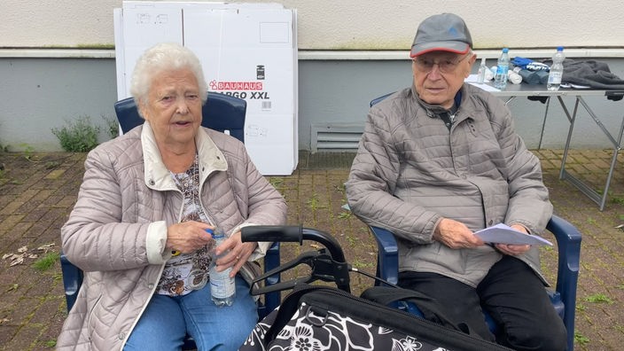 Marianne und Karl-Heinz Fahnenstich auf Campingstühlen, im Hintergrund Umzugskartons