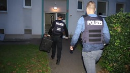 Zwei Polizeibeamte betreten bei Dunkelheit ein Mehrfamilienhaus in Essen-Stoppenberg