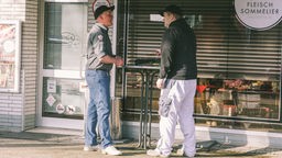 Vor seinem Laden steht Jürgen Bickert mit einem Kunden, der gerade Nuutria-Ragout probiert.