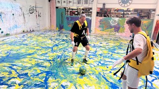 Fußballer laufen über Leinwand und versprühen Farbe