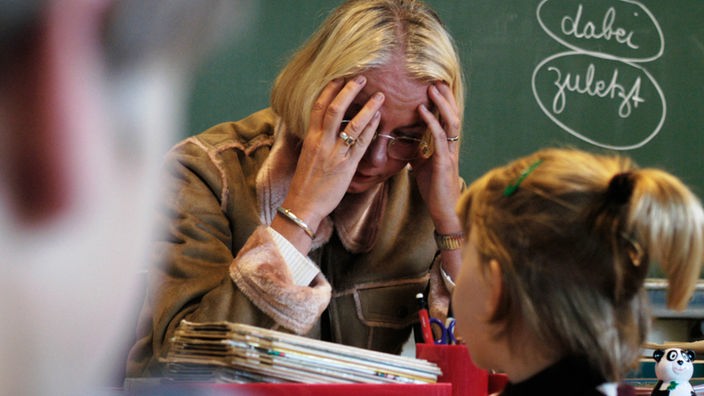 Symbolfoto: Eine Grundschullehrerin sitzt verzweifelt vor ihrer Klasse