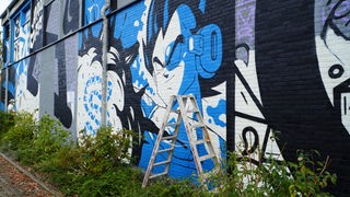 Ein blau-weißes Grafitti zeigt einen Trickfilm-Charakter.