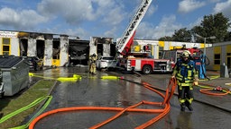 Feuerwehrauto und Feuerwehrmann vor einem abgebrannten Gebäude