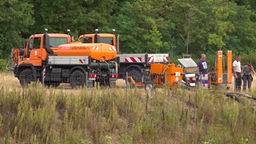orangefarbene Klein-Lkw mit Schläuchen und mehreren Personen