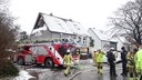 Ein Feuerwehrauto steht vor dem Haus mit der eingestürzten Giebelwand