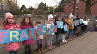 Kinder halten vor der Hertener Schule zusammen Protestschilder hoch