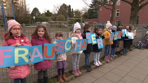 Kinder halten vor der Hertener Schule zusammen Protestschilder hoch