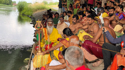 Eine Hindu-Gemeinde sitzt für eine rituelle Waschung am Ufer eines Flusses.