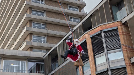 Eine als Nikolaus verkleidetet Person rutsch eine Seilbahn hinab 