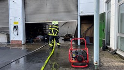 Zwei Feuerwehrleute im Einsatz vor einem Lagerhallen-Tor