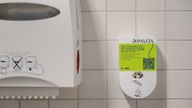 Tampon-Spender an der gefliesten Wand einer Toilette