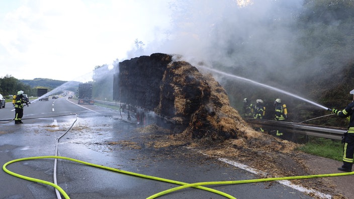 Feuerwehrleute löschen Stroh auf einem Sattelzug