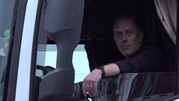 Lkw-Fahrer sitzt bei offenem Fenster in seiner Fahrerkabine und raucht.