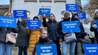 Teilnehmende der Mahnwache stehen vor dem Amtsgericht und halten Schilder in den Händen: "Gerechtigkeit für Tiere" etc.