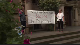 Zwei Menschen halten ein großes Papierschild