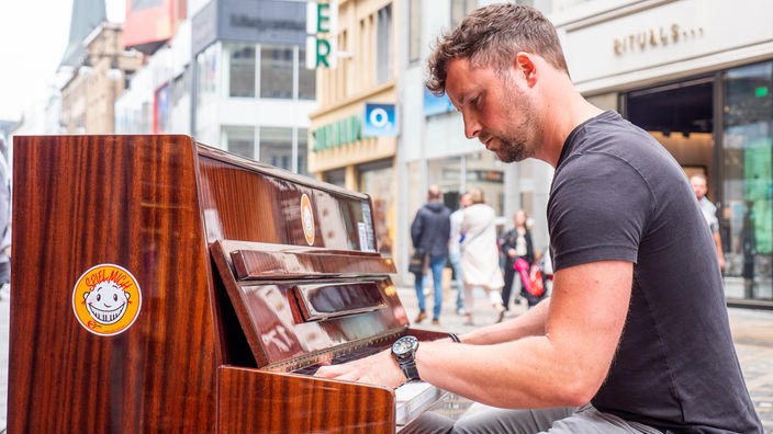 Ein Mann spielt in der Innenstadt Klavier.