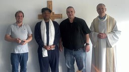 Der Mauretanier mit vier gläubigen Katholiken vor einem Holzkreuz