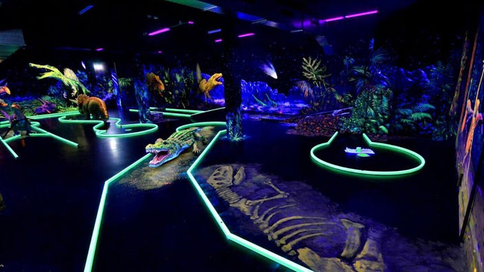 Krokodile und Dinosaurier auf der Minigolfanlage in Neonfarben, Schwarzlicht