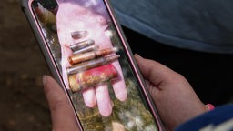 Eine Frau hält ein Handy in der Hand, auf dem ein Foto der Munition zu sehen ist, die an der Lenne gefunden wurde