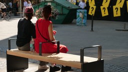 Zwei Frauen sitzen auf einer der neuen Bänke in der Essener Innenstadt