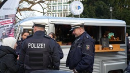 Polizisten im Gespräch mit Bürgerin auf dem Hagener Weihnachtsmarkt