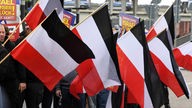 Schwarz gekleidete Männer schwenken auf einer Demonstration der Partei "die Rechte" schwarz-weiß-rote Fahnen