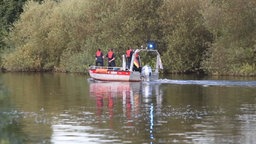 Man sieht ein Rettungsboot auf einem Fluss (Ruhr) und vier Männer in Schwimmwesten