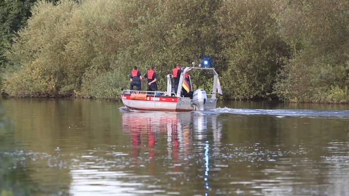 Man sieht ein Rettungsboot auf einem Fluss (Ruhr) und vier Männer in Schwimmwesten